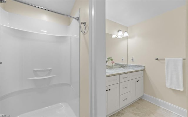 full bathroom with a shower, double vanity, a sink, and baseboards