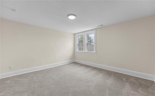 empty room featuring carpet floors, visible vents, and baseboards