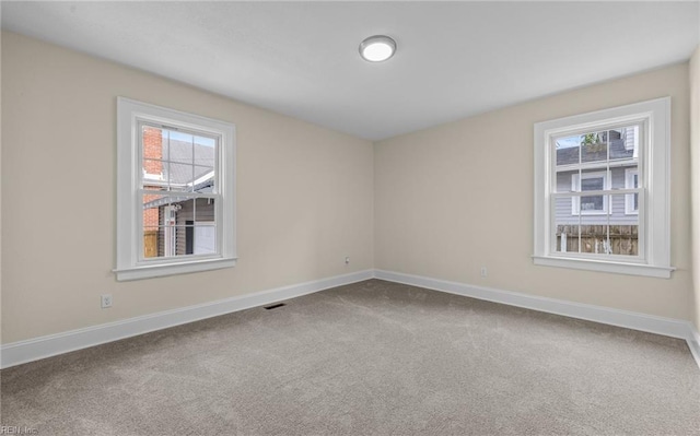 unfurnished room with carpet, visible vents, and baseboards