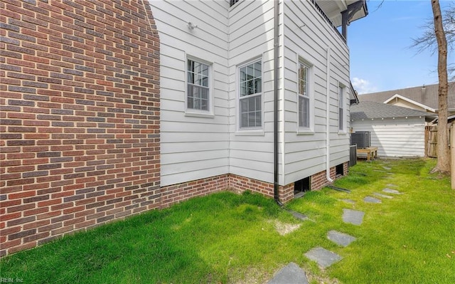 view of side of home with central AC, a lawn, and fence