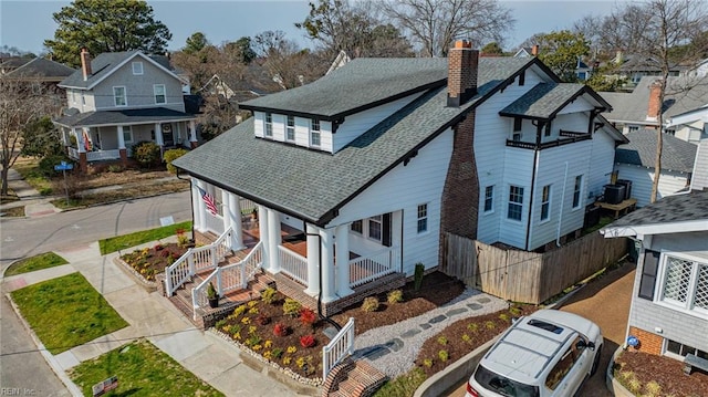 view of front facade with a shingled roof, a chimney, a residential view, fence, and a porch