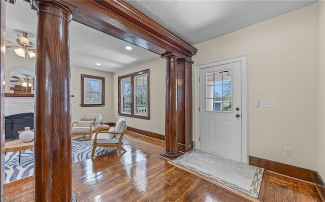 foyer featuring ornate columns, baseboards, a wealth of natural light, and wood finished floors