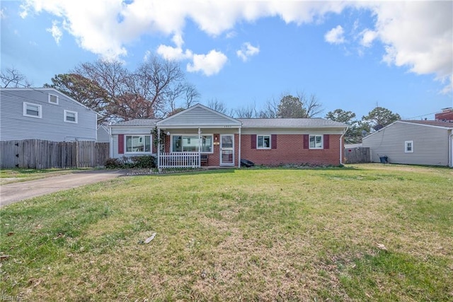 view of front of property featuring covered porch, fence, a front lawn, and brick siding