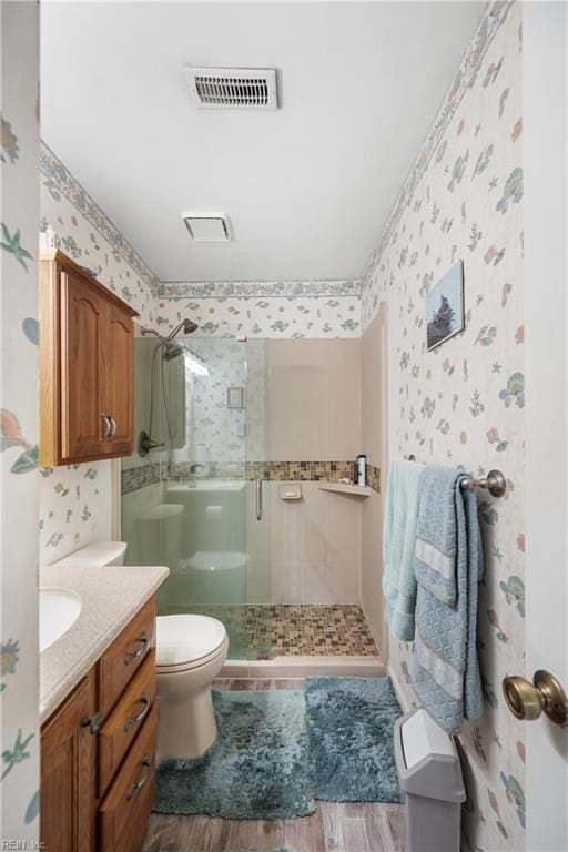 full bathroom featuring visible vents, a shower stall, toilet, and wallpapered walls