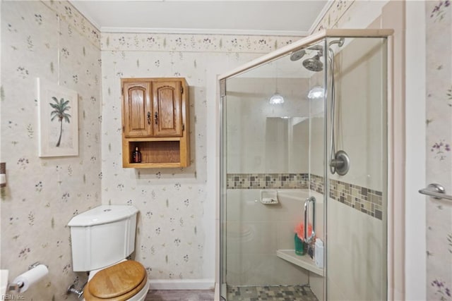 bathroom with crown molding, a stall shower, toilet, and wallpapered walls