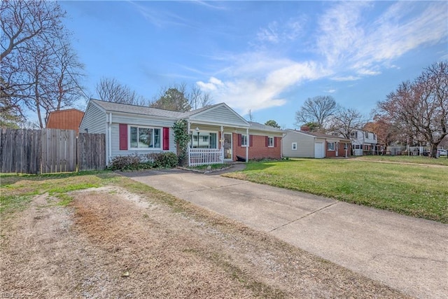 view of front of house featuring brick siding, a porch, a front yard, fence, and driveway