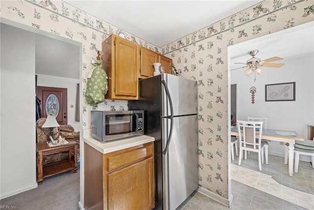 kitchen with wallpapered walls, baseboards, ceiling fan, appliances with stainless steel finishes, and light countertops