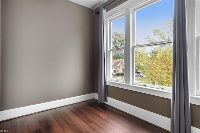 empty room with dark wood-style flooring and baseboards