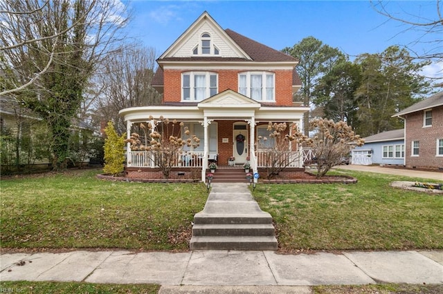 view of front facade with a porch, a front yard, and brick siding