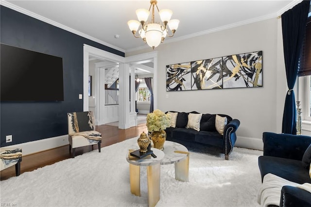 living area with crown molding, a notable chandelier, baseboards, and wood finished floors