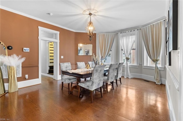 dining space featuring a notable chandelier, visible vents, ornamental molding, wood finished floors, and baseboards