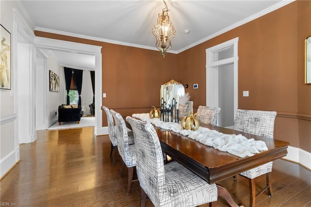 dining area with baseboards, crown molding, an inviting chandelier, and wood finished floors