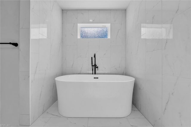 full bathroom featuring marble finish floor and a soaking tub