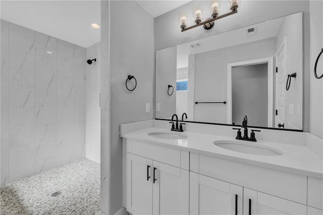 bathroom featuring double vanity, visible vents, a sink, and tiled shower