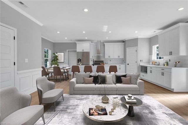 living area with a wainscoted wall, light wood-type flooring, visible vents, and recessed lighting