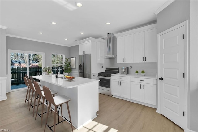 kitchen featuring range with gas stovetop, a center island with sink, stainless steel refrigerator with ice dispenser, a sink, and wall chimney exhaust hood