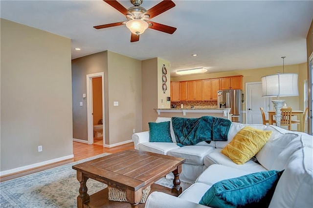 living area featuring ceiling fan, recessed lighting, light wood-style flooring, and baseboards