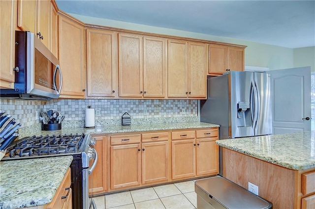 kitchen with light tile patterned floors, appliances with stainless steel finishes, light stone counters, and decorative backsplash