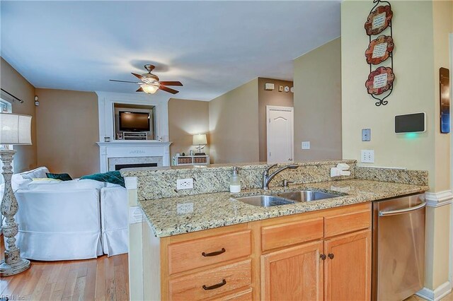 kitchen featuring open floor plan, a large fireplace, ceiling fan, a sink, and light stone countertops