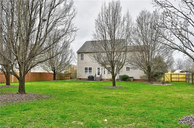 back of house featuring entry steps, crawl space, a fenced backyard, and a yard