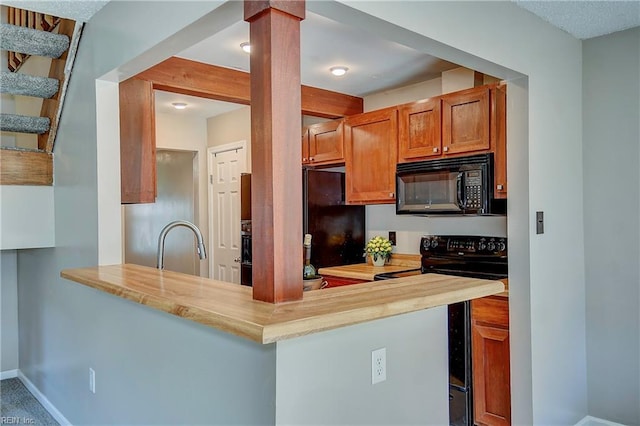 kitchen featuring a sink, baseboards, black appliances, brown cabinetry, and ornate columns