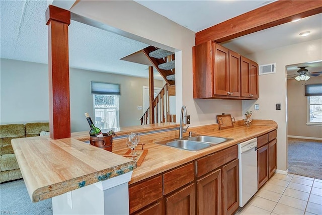 kitchen featuring visible vents, a ceiling fan, a sink, dishwasher, and a peninsula