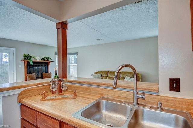 kitchen featuring brown cabinets, light countertops, visible vents, a sink, and a textured ceiling