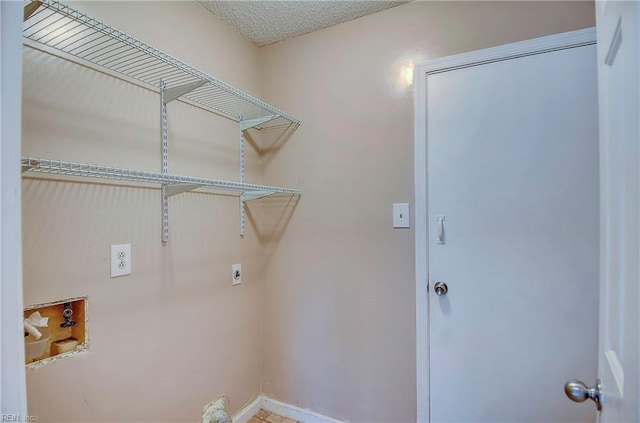 laundry area with laundry area, a textured ceiling, baseboards, and electric dryer hookup