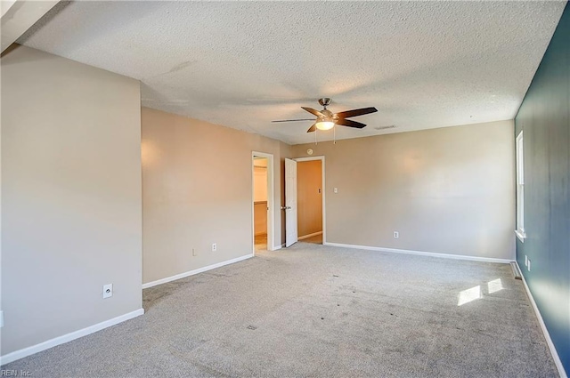 carpeted empty room with a ceiling fan, visible vents, a textured ceiling, and baseboards