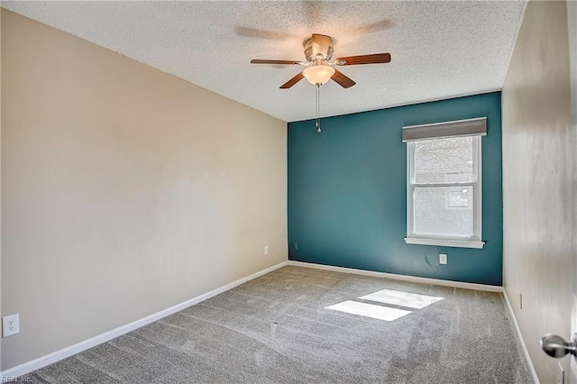 carpeted empty room with ceiling fan, baseboards, and a textured ceiling