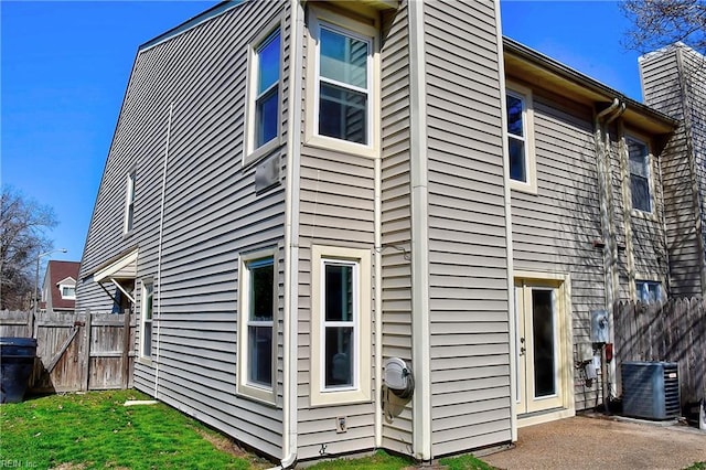 view of home's exterior featuring a chimney, fence, cooling unit, and a patio