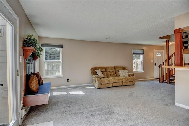 living room featuring stairs, baseboards, carpet flooring, and a healthy amount of sunlight