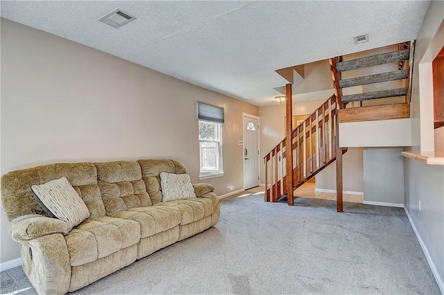 carpeted living area featuring stairs, a textured ceiling, visible vents, and baseboards