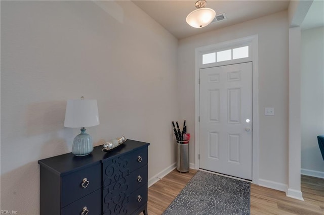 foyer entrance featuring visible vents, light wood-style flooring, and baseboards