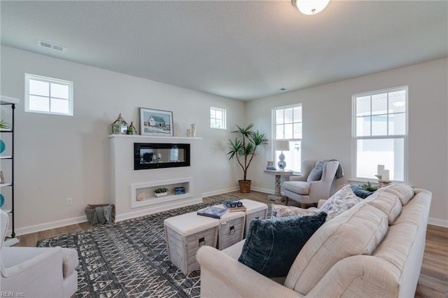 living area featuring baseboards, visible vents, and wood finished floors