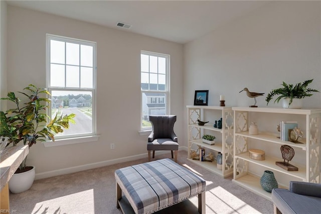 living area with carpet floors, visible vents, and baseboards