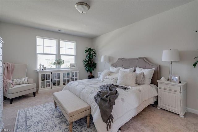 bedroom featuring baseboards, visible vents, and light colored carpet