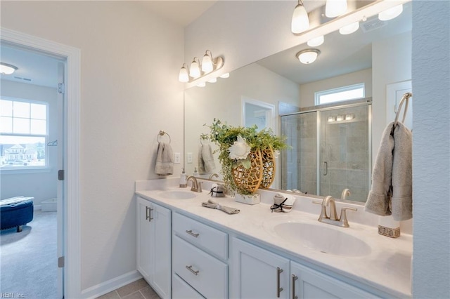 bathroom featuring baseboards, double vanity, a sink, and a shower stall