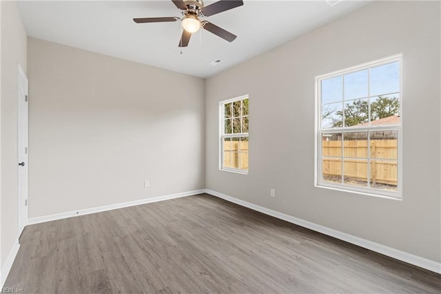 empty room with ceiling fan, baseboards, and wood finished floors