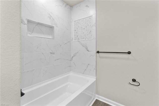 full bath with baseboards, shower / washtub combination, and a textured wall