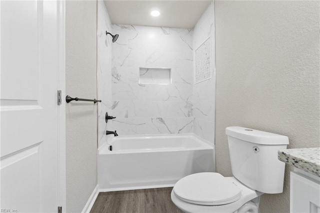 full bathroom featuring toilet, tub / shower combination, wood finished floors, and a textured wall