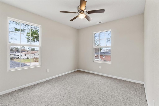 carpeted empty room featuring ceiling fan, visible vents, and baseboards