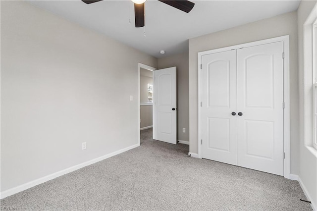 unfurnished bedroom with ceiling fan, a closet, carpet, and baseboards