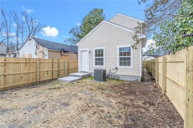 rear view of house with central AC unit and a fenced backyard