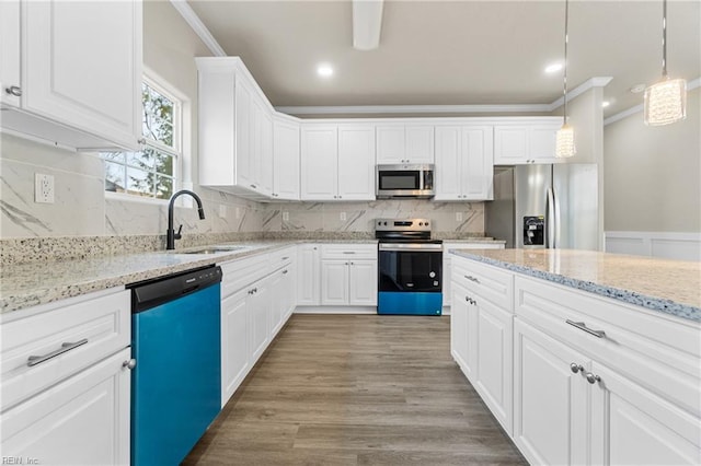 kitchen with light wood-style flooring, ornamental molding, stainless steel appliances, and a sink