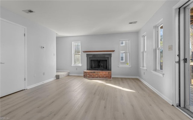 unfurnished living room with light wood-style floors, visible vents, a fireplace, and baseboards