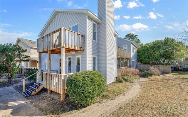 view of side of property featuring a chimney, fence, and a balcony