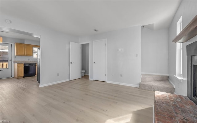 unfurnished living room featuring baseboards, a brick fireplace, and light wood-style floors