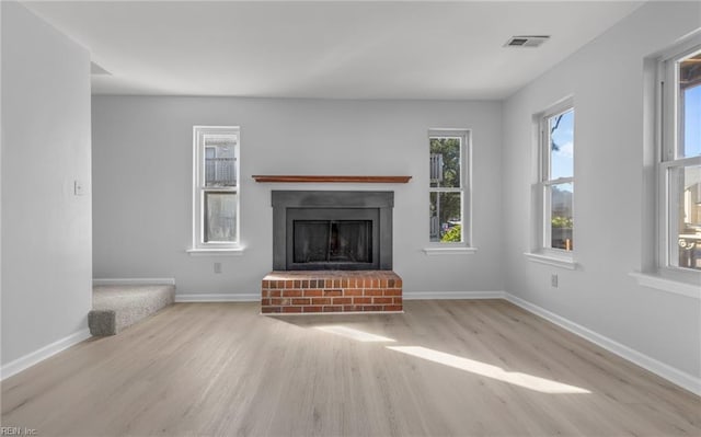 unfurnished living room with visible vents, a fireplace, baseboards, and wood finished floors