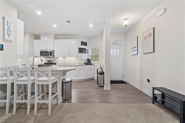 kitchen with a breakfast bar area, recessed lighting, visible vents, white cabinetry, and appliances with stainless steel finishes